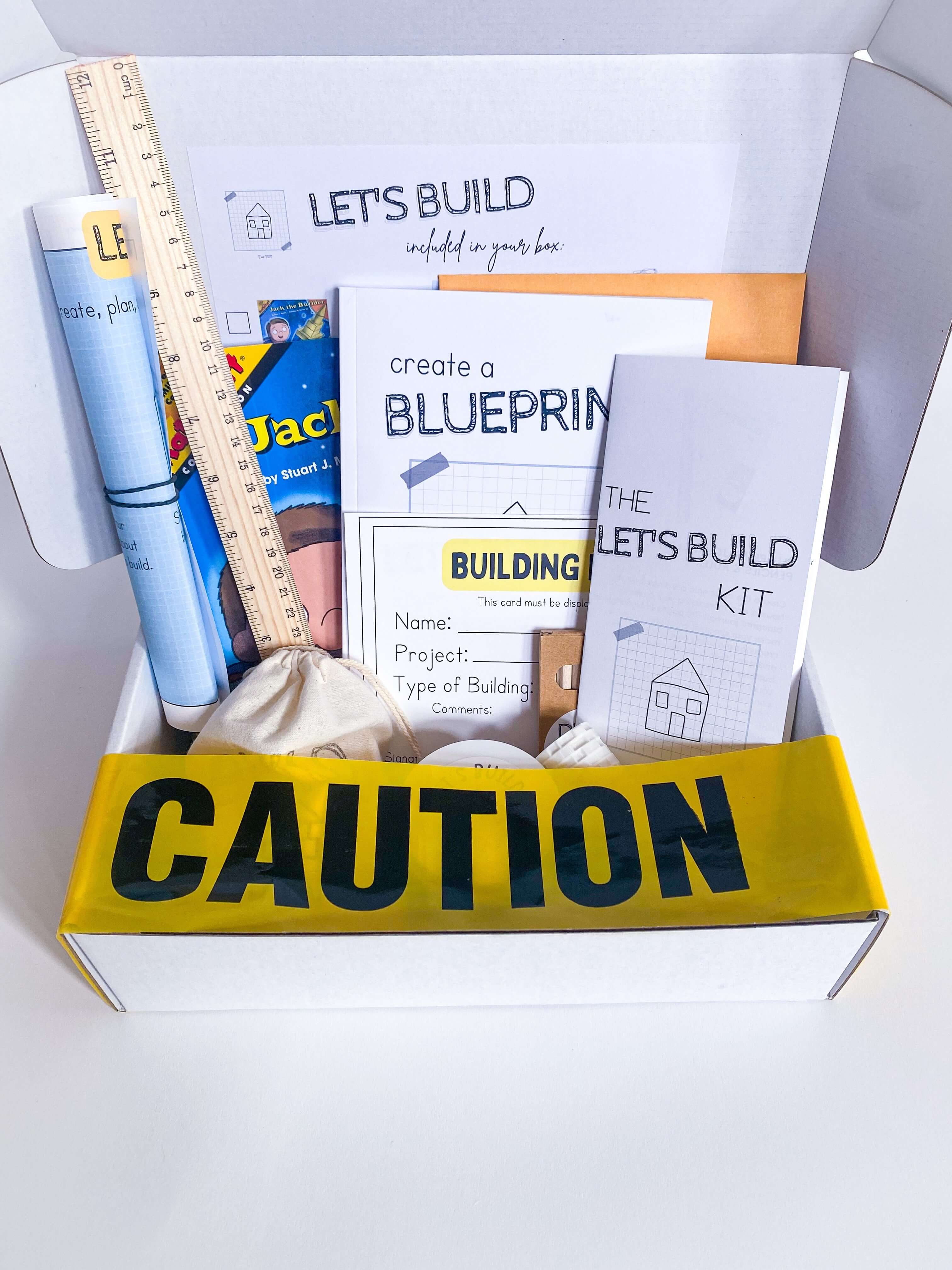 Play-based construction kit for children with homemade non-toxic playdough, brick playdough roller, building blocks, and role play items like blueprint and caution tape. Comes with a blueprint journal, ruler, and 